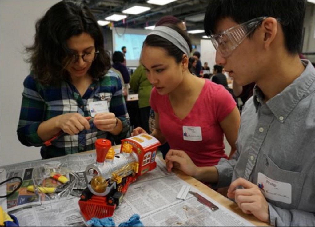 A team of volunteer students work together to solder an adaptive switch onto a toy in time for the holidays.