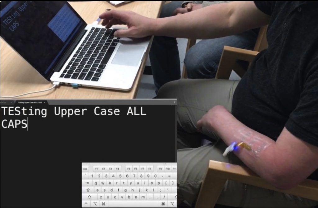 A user wears a flexible electrode on their forearm and uses the electrode to control the shift key on their laptop.