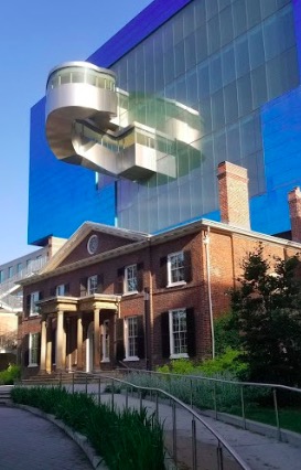 Modern meets colonial architecture at the huge Toronto Art Museum. An old colonial building sits in front of the modern, glass-fronted art museum.