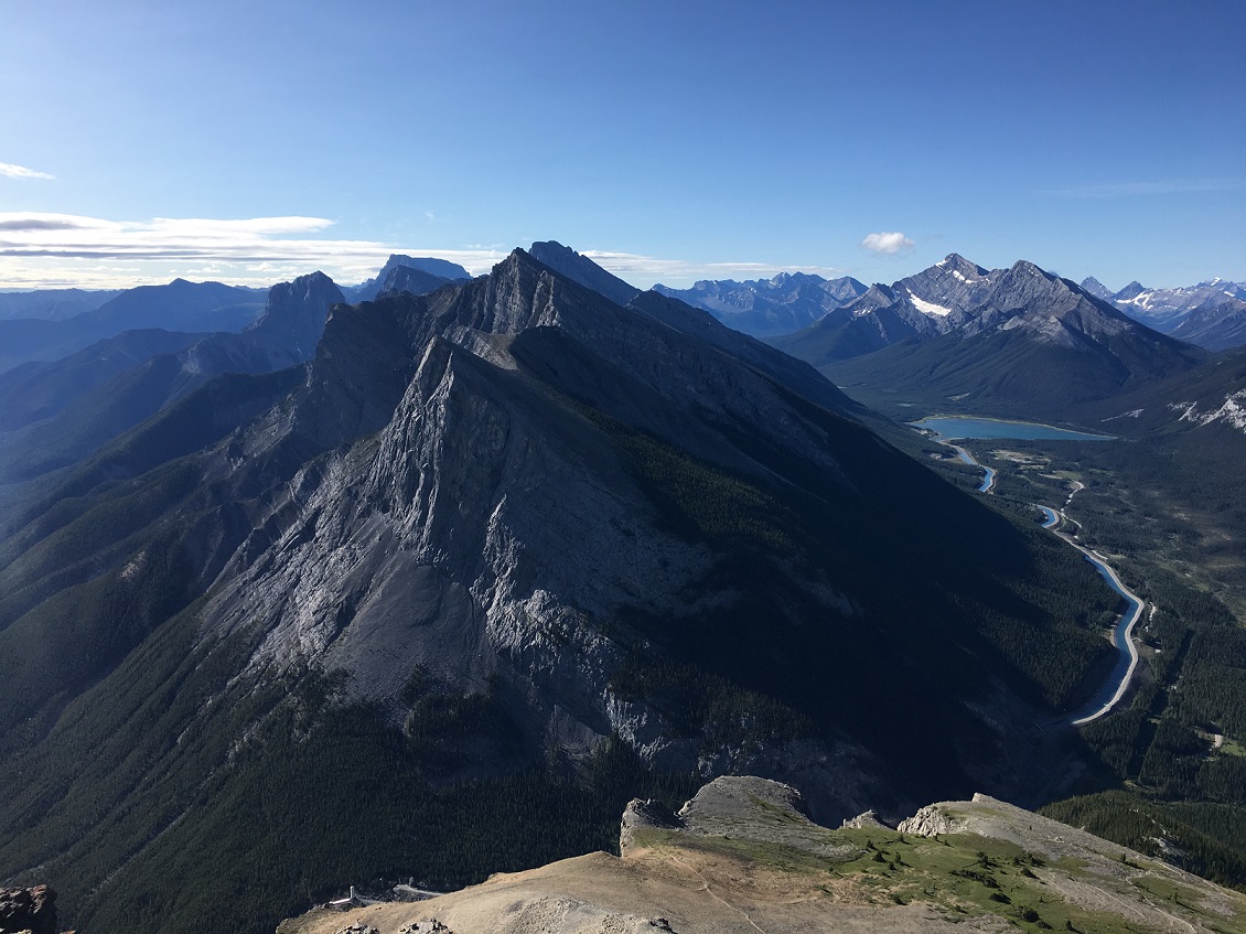 A mountain view in Canmore, Canada with sharp jagged peaks and a bright blue lake.