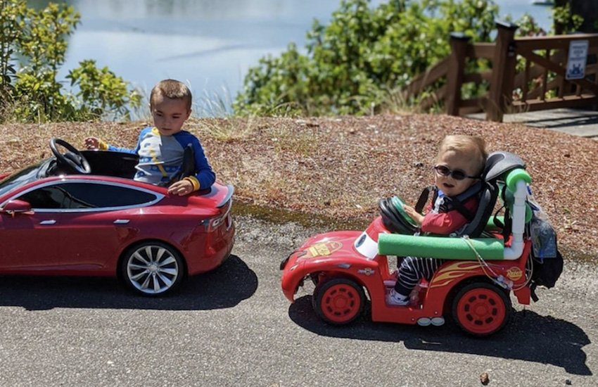 Two children are riding adapted toy cars