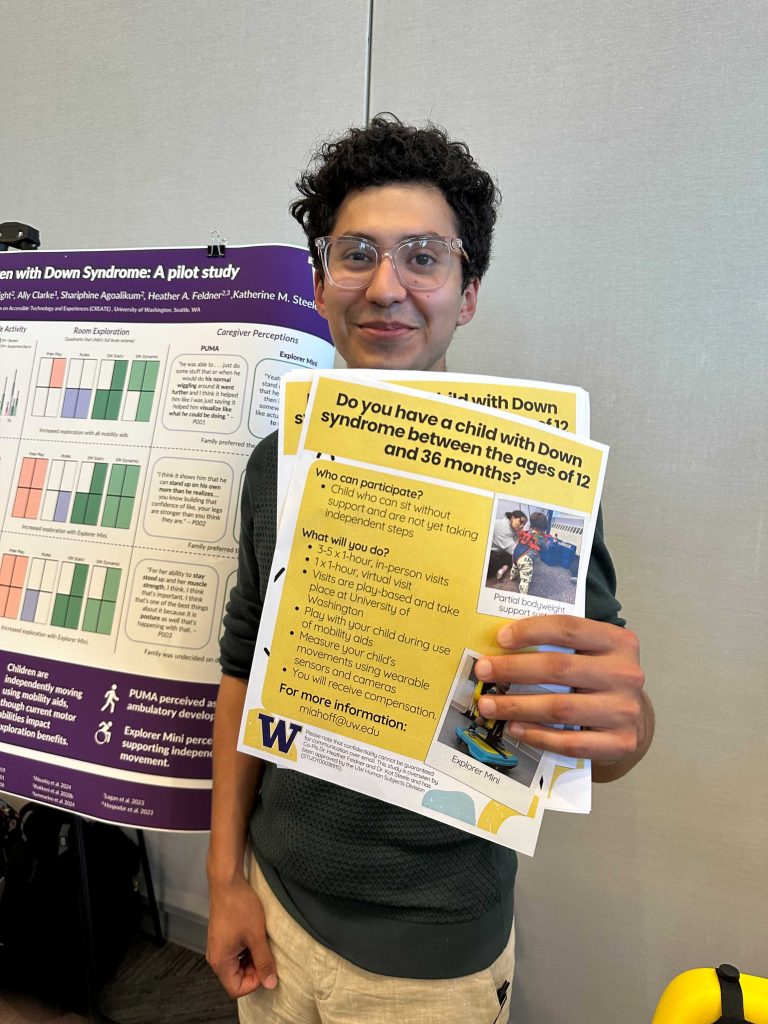 A person holding a flyer in front of a research poster about Down syndrome. The flyer invites families with children aged 12–36 months with Down syndrome to participate in a study at the University of Washington.
