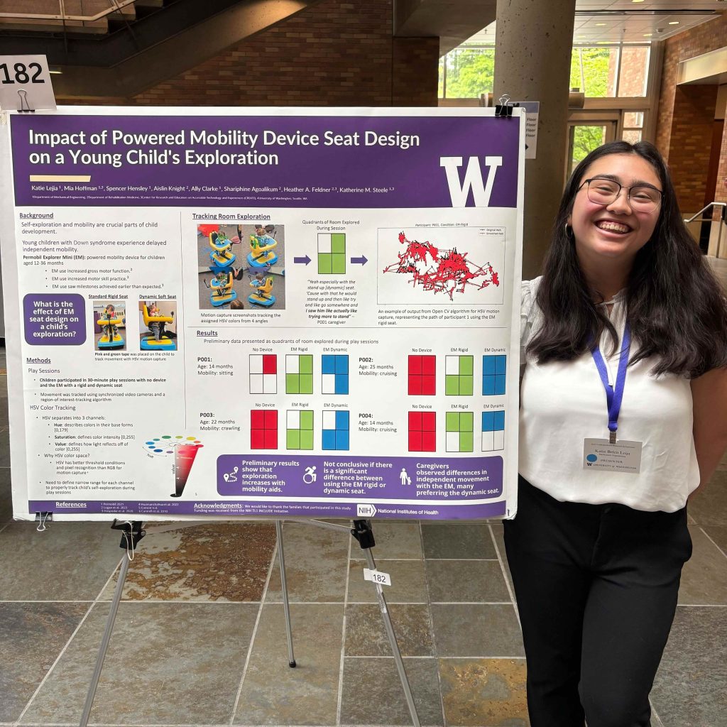A person stands next to a research poster titled “Impact of Powered Mobility Device Seat Design on a Young Child's Exploration,” featuring the University of Washington logo.