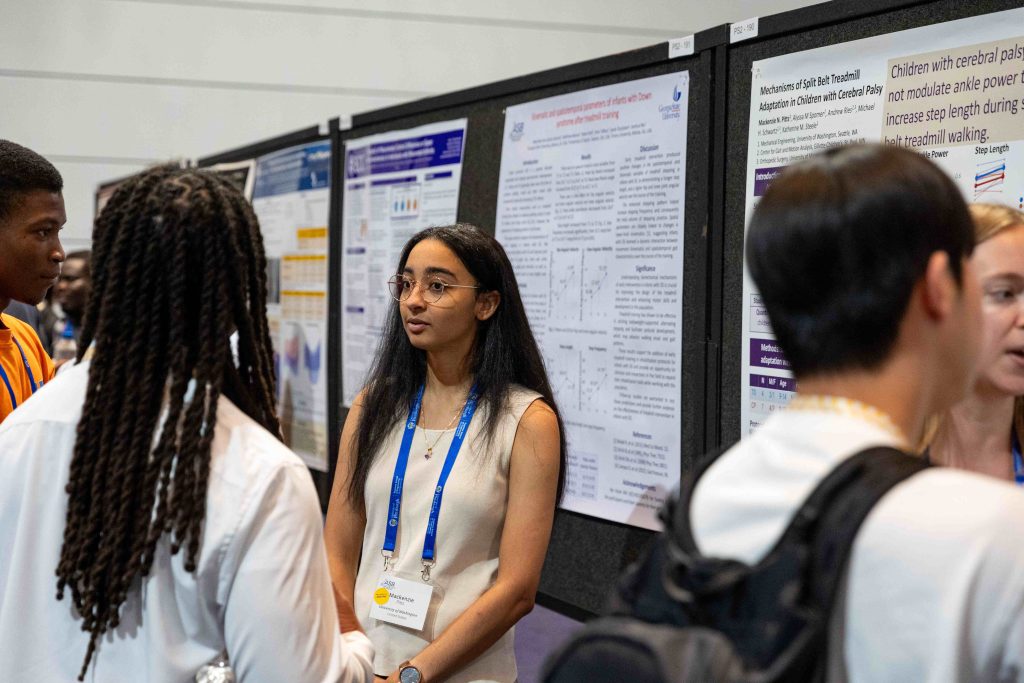 Group of individuals standing and discussing research in front of scientific posters at ASB 2025, with charts and graphs visible on the posters