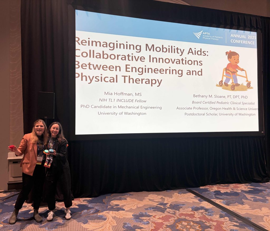 Two presenters stand in front of a large projection screen displaying the session title “Reimagining Mobility Aids: Collaborative Innovations Between Engineering and Physical Therapy” at the APTA Pediatrics 2025 Conference. The slide includes names, credentials, and affiliations for Mia Hoffman and Bethany M. Sloane. The background shows patterned carpet and a dark curtain framing the screen.