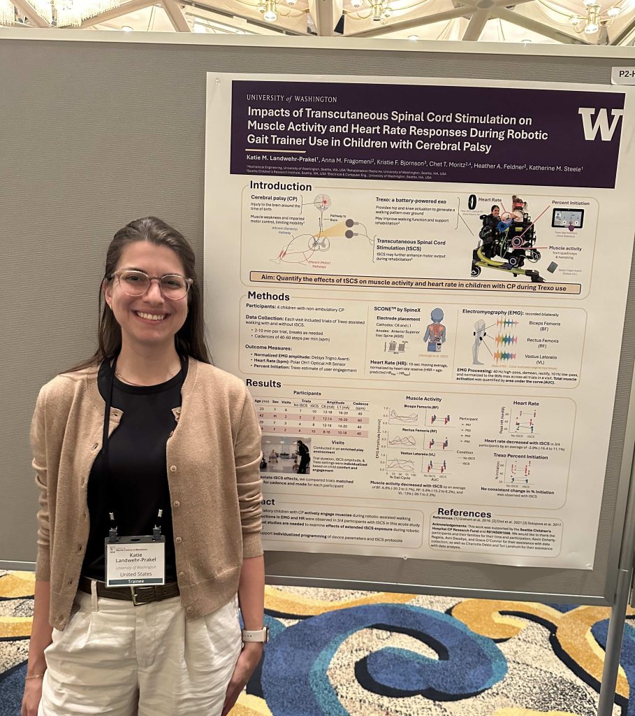 Katie stands in front of a scientific poster titled “Impacts of Transcutaneous Spinal Cord Stimulation on Muscle Activity and Heart Rate Responses During Robotic Gait Trainer Use in Children with Cerebral Palsy” at a poster session.