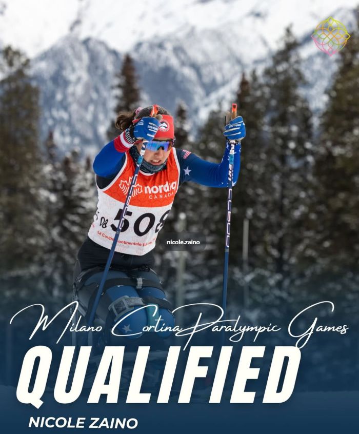 Para Nordic sit‑skier races on snow using poles, wearing a Team USA racing bib, with snowy mountains and evergreen trees in the background. Text on the image reads, “Milano Cortina Paralympic Games – Qualified – Nicole Zaino.”